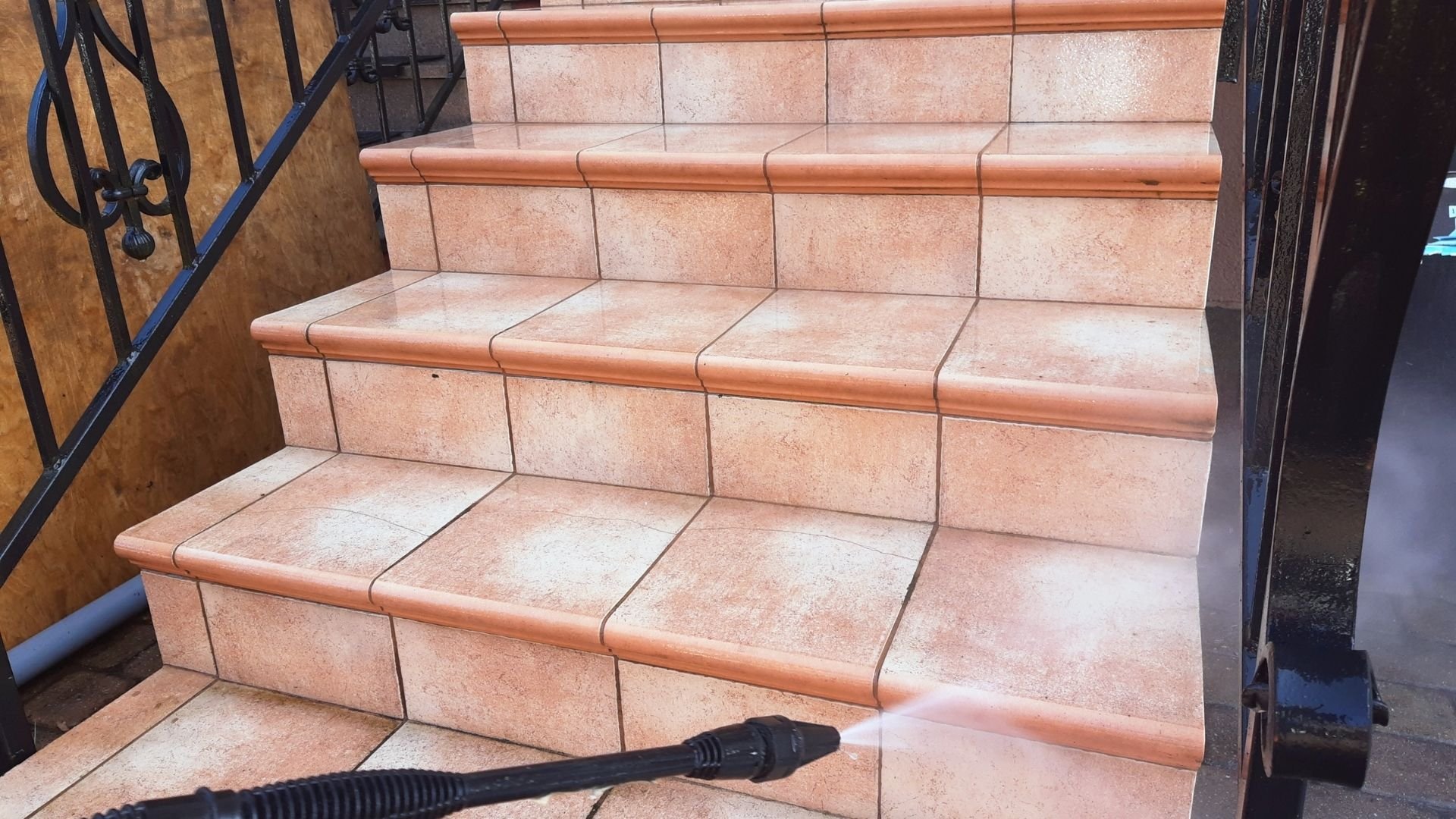 Terracotta tile staircase with copper trim and metal railing, outdoor entrance area.