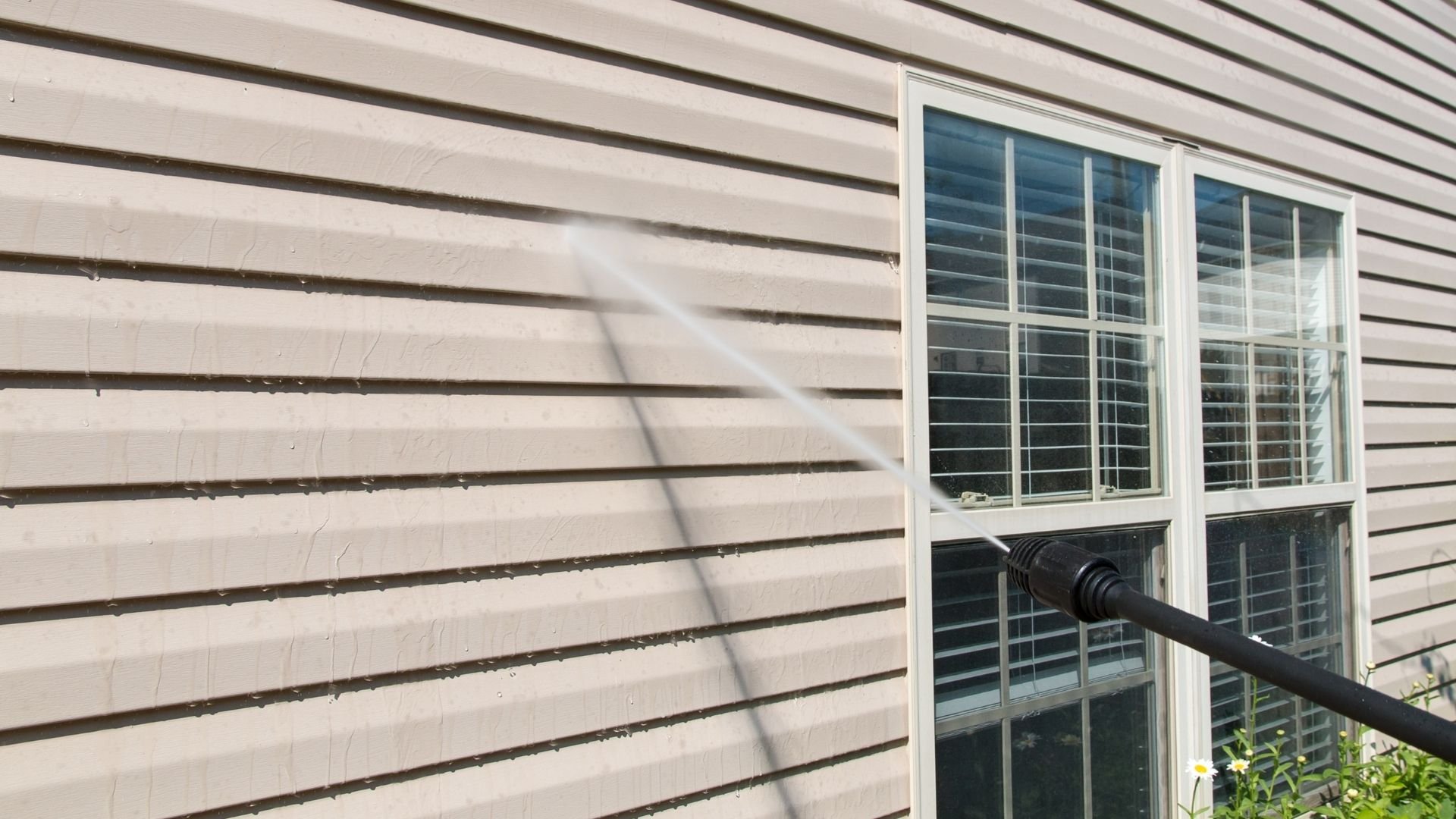House exterior with beige horizontal siding, large window, and gutter downspout